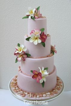 a pink three tiered cake with flowers on top