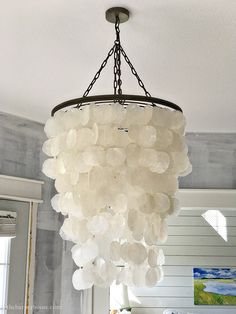 a chandelier hanging from the ceiling in a room with white walls and windows