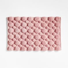 a pink bath mat with circles on the bottom and one circle in the middle, against a white background