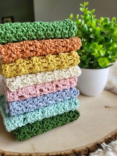 a stack of crocheted dishcloths sitting next to a potted plant