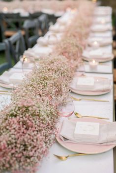 the table is set with place settings and flowers in vases on each one side