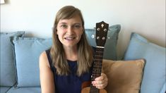 a woman sitting on a couch holding an ukulele