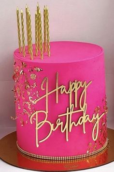 a pink birthday cake with gold candles on top