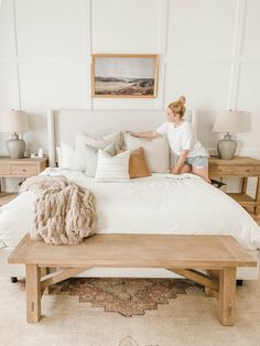 a woman sitting on top of a bed in a bedroom