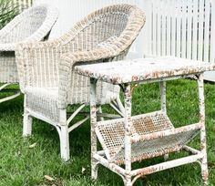 three wicker chairs sitting in the grass next to a white picket fence