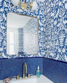 a bathroom with blue and white tiles on the wall, sink and mirror in it