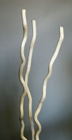 two white vases sitting next to each other on top of a wooden table in front of a gray wall