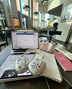 an open laptop computer sitting on top of a table next to two hello kitty shoes