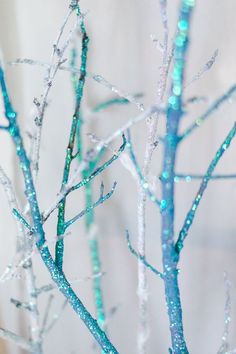 the branches are covered in blue and white glittery paint, with small drops of water on them