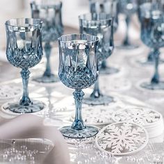 many crystal goblets are lined up on a tablecloth with snowflakes