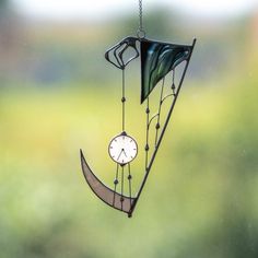 a wind chime hanging from a chain with a clock on it's side