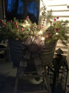 a christmas tree in a bucket with lights on the top and decorations hanging from it