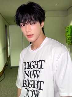 a man with black hair wearing a white t - shirt and looking at the camera