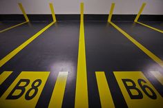 an empty parking garage with yellow lines painted on the floor and white wall behind it