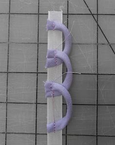 a piece of white fabric with purple ribbon on it sitting on top of a tile floor