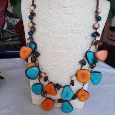 Handcrafted Tagua And Acai Seed Artisanal Necklace Made In Ecuador. Bright Summer Colors That Will Go Perfectly With White, Beige And Black Color Outfits. Tagua Nuts Come From The Amazonia Rainforest Of Ecuador, Acai Seeds Are From Brasil Rain Forests And Ate Imported By Ecuadorian Artisan Jewelry Makers Because Acai Looks Very Suitable In Combination With T Agua Chips. Casual Multicolor Fair Trade Jewelry, Adjustable Blue Fair Trade Necklace, Fair Trade Multicolor Beach Jewelry, Fair Trade Multicolor Jewelry For Beach, Multicolor Fair Trade Jewelry For The Beach, Blue Fair Trade Beaded Necklaces For Festivals, Artisan Orange Adjustable Necklace, Artisan Adjustable Orange Necklace, Adjustable Orange Artisan Necklace