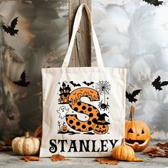 a tote bag sitting on top of a table next to pumpkins and bats