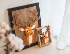 the beaded deer is hanging on the wall next to a framed photo and flowers