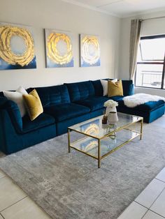 a living room with blue couches and two paintings on the wall above them, along with a coffee table