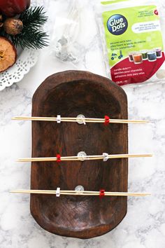 four skewers on a wooden plate with pine cones and other holiday decorations around them