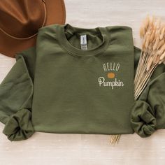 Welcome the cozy vibes of fall with our "Hello Pumpkin" embroidered crewneck! This comfy sweatshirt is made from a soft 50/50 cotton polyester blend, offering both warmth and durability. Whether you're sipping on a pumpkin spice latte or enjoying a crisp autumn walk, this crewneck is the perfect addition to your fall wardrobe. Product Details:Material: Cozy 50/50 cotton polyester blend for a soft, comfortable feelDesign: Fall-themed "Hello Pumpkin" design featuring a charming pumpkin accent embroidered on the left chestFit: Unisex sizing from S to 2XL, offering a relaxed fit that's perfect for layeringColors Available: Ash, Black, Maroon, Military Green, Navy, Sand, Forest Green, Sport Grey, WhiteCare Instructions: Machine wash cold, tumble dry low for best results Please Note: Colors may Green Cotton Sweater For Fall, Trendy Tops With Custom Embroidery For Fall, Fall Sweatshirt For Loungewear With Embroidered Text, Fall Loungewear Sweatshirt With Embroidered Text, Green Fall Sweater With Embroidered Logo, Fall Green Sweater With Embroidered Logo, Green Sweater With Embroidered Logo For Fall, Green Embroidered Logo Sweater For Fall, Trendy Embroidered Logo Sweater For Fall