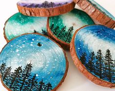 painted wood slices with trees on them and stars in the sky above it, sitting on a white surface