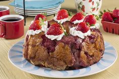 a bundt cake with strawberries and whipped cream on top sitting on a plate