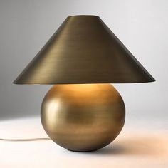 a gold lamp with a black shade on the bottom and a white background behind it