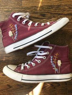 two pairs of red converse sneakers with embroidered flowers on them