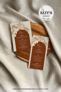 two brown and white wedding programs on a wooden plate