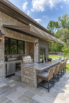 an outdoor kitchen and dining area with stone counter tops, grilling station and chairs