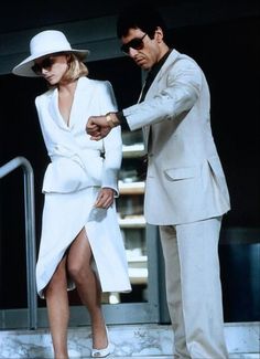 a man in a white suit and hat standing next to a woman