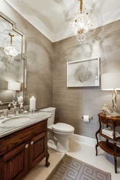 a white toilet sitting next to a bathroom sink under a chandelier in a bathroom