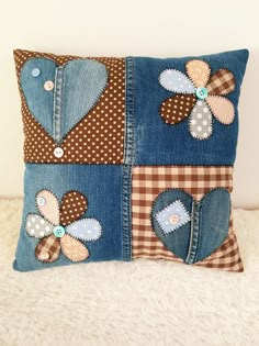 a decorative pillow made out of old jeans with patches and flowers on the front, sitting on a white furnishing