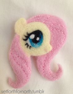 a close up of a pink and white brooch with an eyeball on it