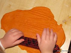 a child is making something out of clay on a wooden surface with their hands and fingers