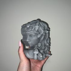 a woman's hand holding a sculpture of a female head