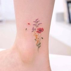 a woman's foot with flowers and leaves on the bottom part of her ankle