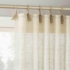 the curtains are hanging in front of the window with rope on them and two tassels at the top