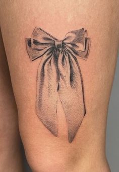 a woman's thigh with a bow tattoo on it