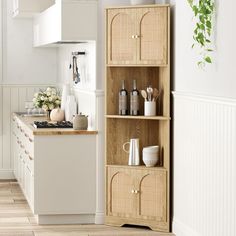 a kitchen with white walls and wooden shelves filled with bottles, cups and utensils