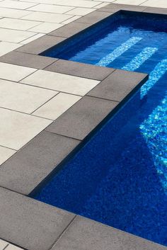 an empty swimming pool with steps leading to the water's edge and tiled flooring