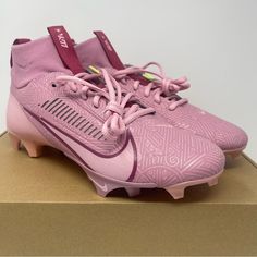 a pair of pink nike soccer cleats on top of a cardboard shoe box