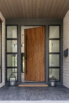 a large wooden door sitting on the side of a brick wall next to two windows