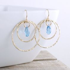 "The perfect gold hoop earrings to be classy for work, and also to dress up with jeans and heels for the evenings and weekends. These gold hammered hoop earrings are about 1.25\" in diameter (the circle) and they hang 1.75\" from the top of the ear wire. It is all 14k gold fill including the ear wire, with gorgeous crystals hanging in the center of the hammered circles. (shown in Aquamarine and Light Turquoise) These earrings are the perfect gift for yourself or anyone on your list. They transit Crystals Hanging, Amazing Earrings, Turquoise Hoop Earrings, Dangle Earrings Gold, Hammered Hoop Earrings, Gem Earrings, Earring Ideas, Crystal Hoop Earrings, Crystal Dangle Earrings