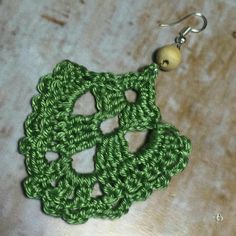 a pair of green crocheted earrings on top of a table