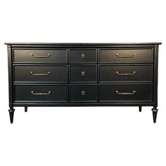 a large black dresser with gold handles and knobs on the top, against a white background