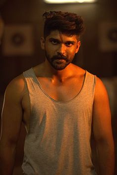 a man standing in a dark room wearing a tank top