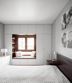 a bedroom with white walls and built - in bookshelves has a window to let light into the room