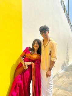 a man and woman standing next to each other in front of a yellow and white wall